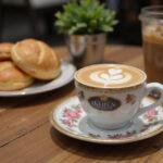 Elegant final presentation of John Brown's coffee with pastries, demonstrating the perfect coffee experience in a cozy café setting.