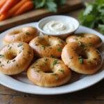 Delicious golden-brown gluten-free bagels arranged on a plate, perfect for enjoying with cream cheese and fresh vegetables, ideal gluten-free breakfast or snack.