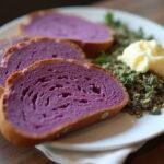 Artfully presented vibrant purple bread on a plate, accented with butter and herbs, perfect for showcasing homemade unique bread.