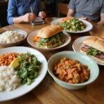Affordable meals on a wooden table, featuring sandwiches, salads, and rice bowls, costing less than USD2 each.