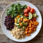 Plate of gut-friendly vegetarian meal with vegetables, grains, and legumes on a wooden table.