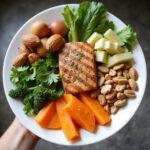 A colorful clean eating plate with fresh vegetables, fruits, nuts, and lean protein for hormone support