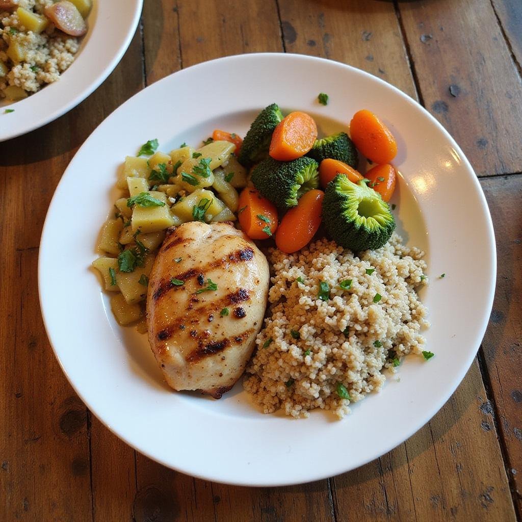 Healthy comfort food plate with grilled chicken, vegetables, and quinoa on wooden table.