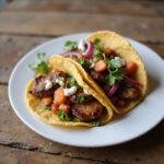 Close-up of a fusion taco with grilled meat, colorful vegetables, and zesty sauces on a rustic wooden table, showcasing a mix of cultural flavors