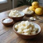 Homemade kitchen scrubs made from food ingredients like sugar, lemon, and coconut oil on a wooden countertop.