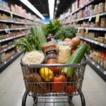 Shopping cart with budget-friendly ingredients such as rice, beans, vegetables, and eggs for a week's cooking on a budget of USD20.
