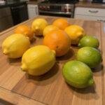 Fresh citrus fruits such as lemons, oranges, and limes on a kitchen counter, used for natural fridge cleaning.