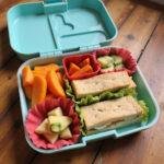A vibrant lunchbox filled with sandwiches, sliced fruits, and vegetable sticks ready for kids to enjoy.