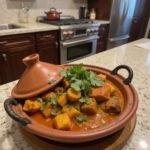 Moroccan tagine dish in a clay pot with fresh herbs on a kitchen countertop, demonstrating how to make tagines without a traditional tagine.