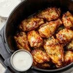 Crispy Air Fryer Hot Honey Lemon Pepper Chicken Wings arranged on a plate, garnished with lemon wedges and sprinkled with pepper.