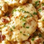 A plate of creamy smothered chicken served over fluffy rice, garnished with fresh herbs and drizzled with rich sauce.