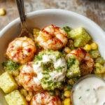 A vibrant grilled shrimp bowl topped with sliced avocado, colorful corn salsa, and drizzled with creamy sauce, served in a rustic bowl.