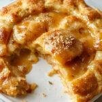 A slice of salted honey pie on a rustic plate, showcasing a golden-brown crust and a glossy honey filling sprinkled with sea salt.