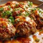 A close-up of a bowl filled with golden-brown homemade meatballs, glazed with a rich tomato sauce. The meatballs are arranged attractively, with steam gently rising, highlighting their juicy texture and crispy exterior. The background features a rustic wooden surface, enhancing the warm, inviting feel of the dish.