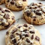 A plate of Spooky & Sweet Oreo Spiderweb Scones decorated with icing spiderwebs and sprinkles, perfect for Halloween.