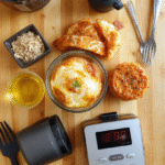 Overhead flat lay of high-quality kitchen gadgets on a warm oak countertop: silicon tongs, a digital thermometer, chef’s knife, silicone spatulas, microplane grater, and a mandoline slicer arranged neatly beside fresh herbs and citrus, soft natural light casting gentle shadows.